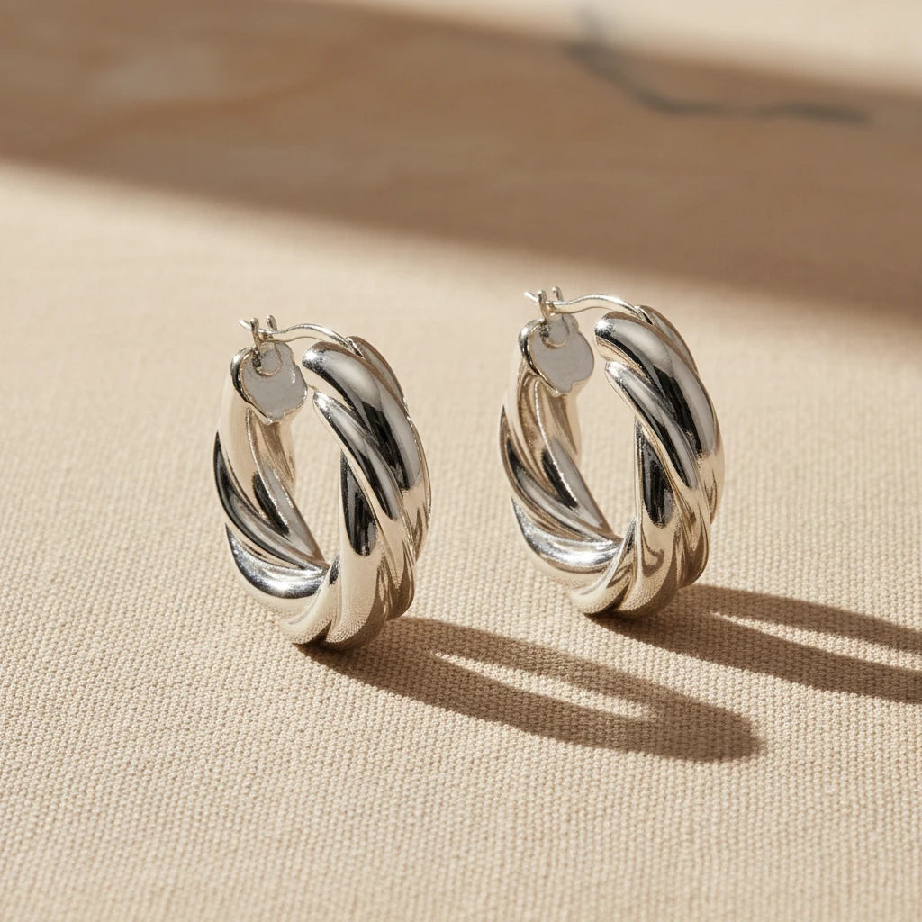Pair of silver twist hoop earrings on a white background