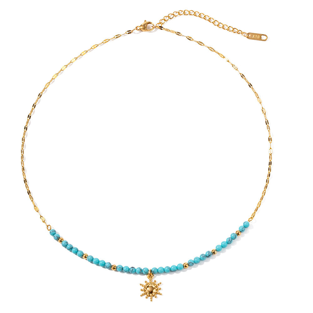 Necklace with turquoise beads and a gold sun  pendant on a white background