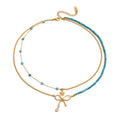 Two layered necklaces with gold and blue turquoise stone beads with a bow and flower on a white background