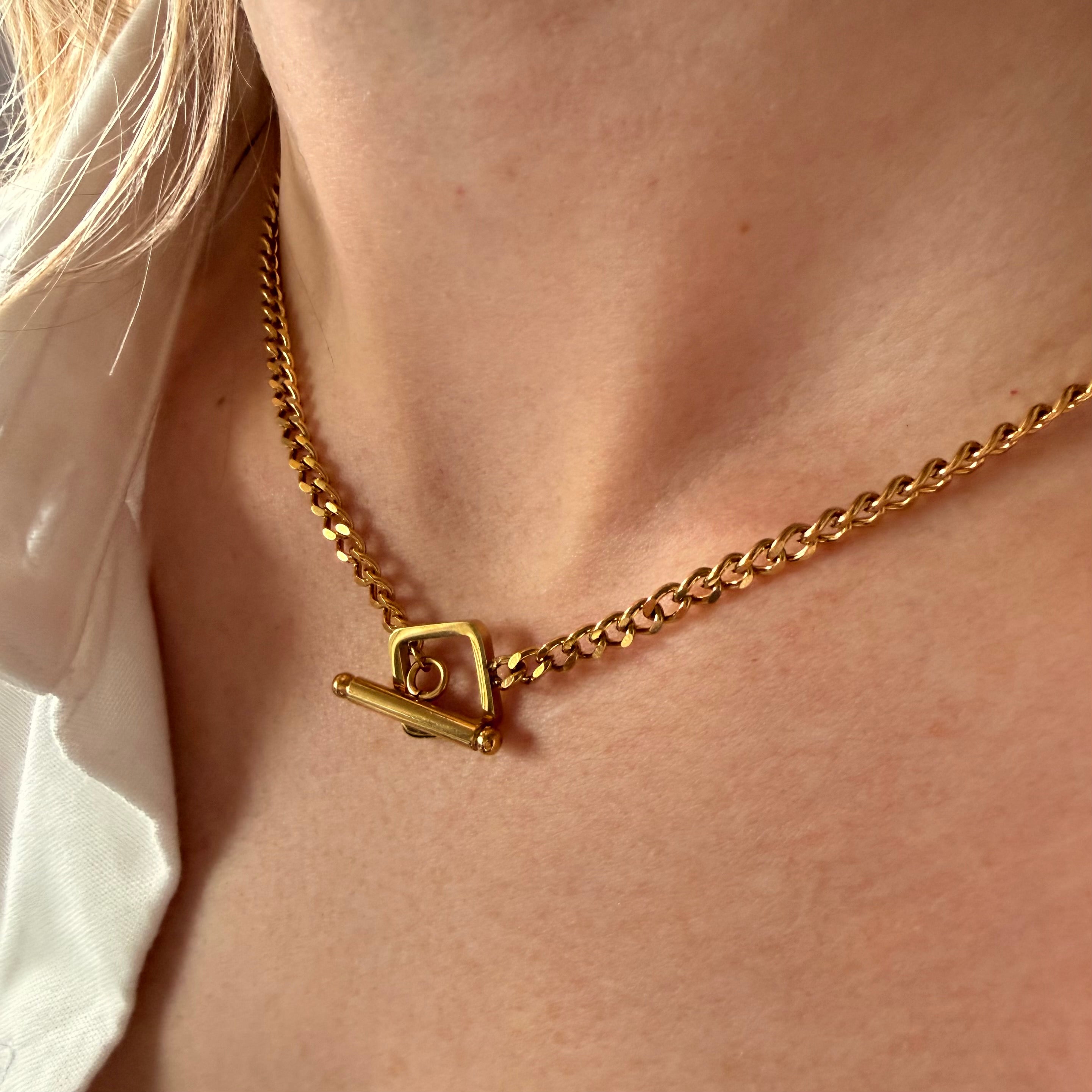 Gold cable chain necklace with a square OT clasp on a person's neck