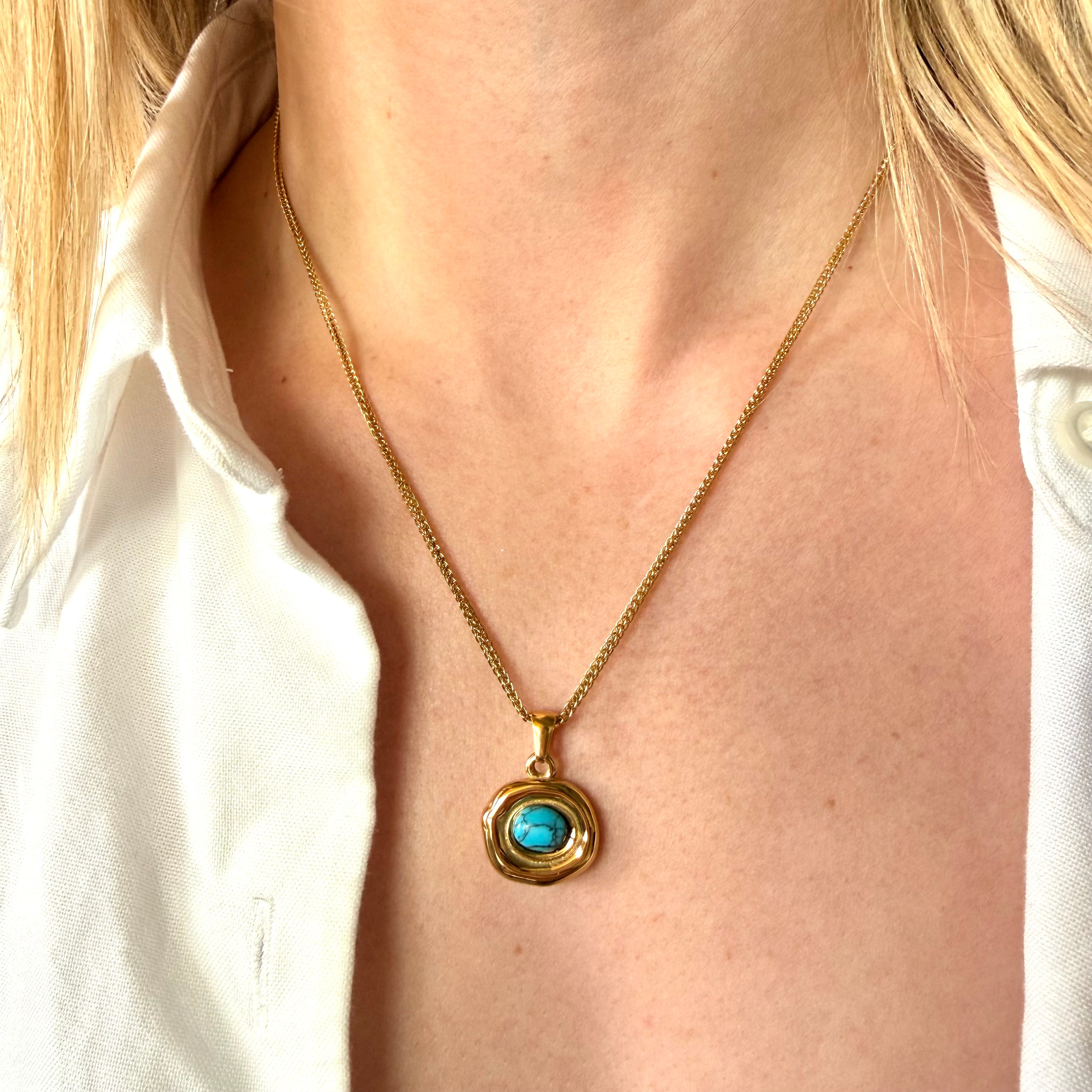 Gold necklace with a turquoise pendant worn by a person in a white shirt. turquoise pendant necklace gold, geometric stone necklace, blue stone necklace
