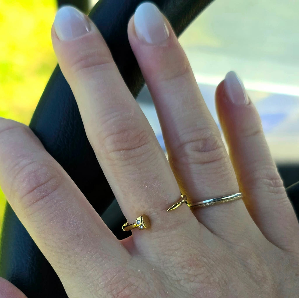 Close-up of a hand wearing two gold rings driving golf cart