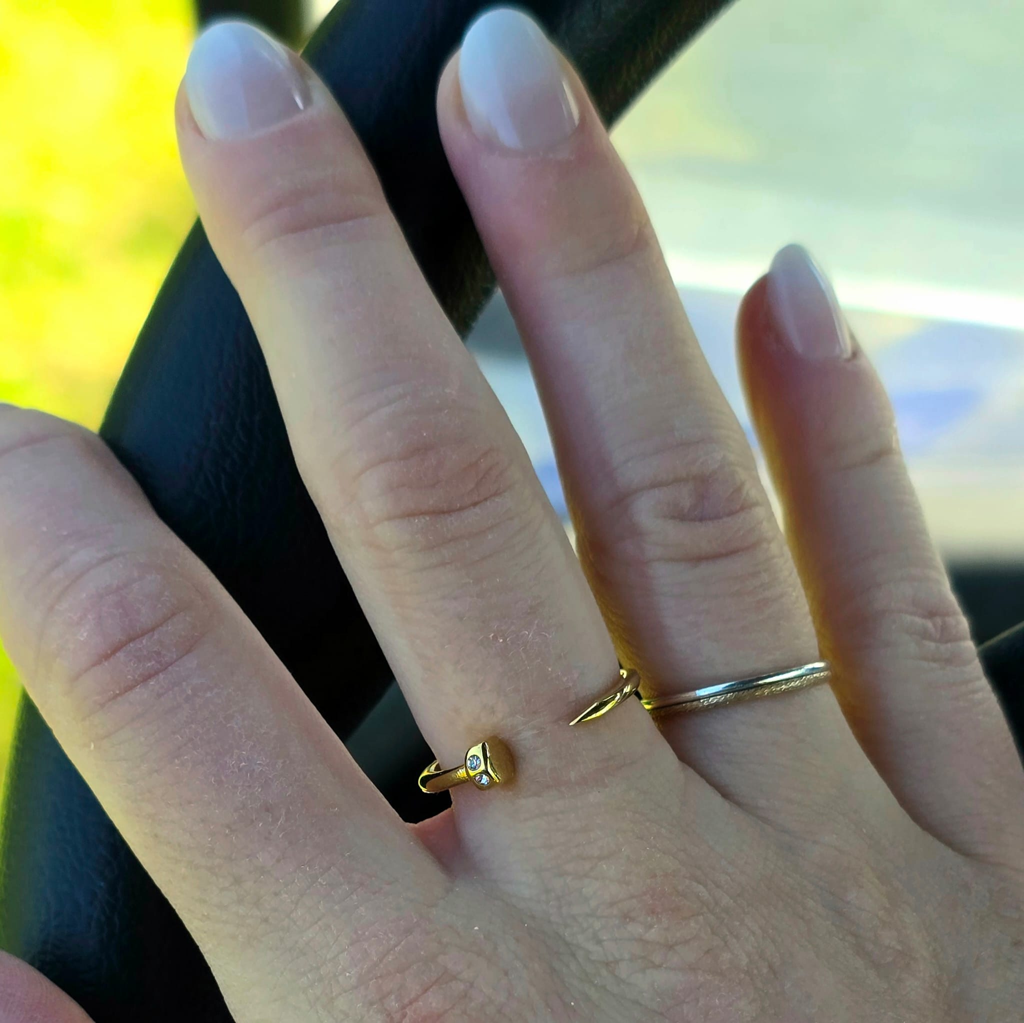 Close-up of a hand wearing two gold rings driving golf cart