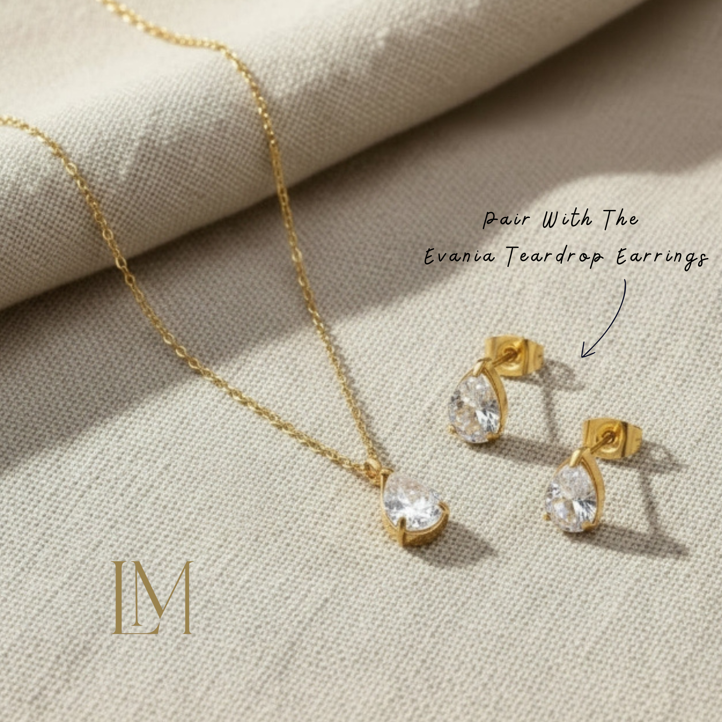 Gold necklace and earrings on a beige fabric background with 'LM' logo.