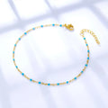 Gold anklet with blue beads on a white background