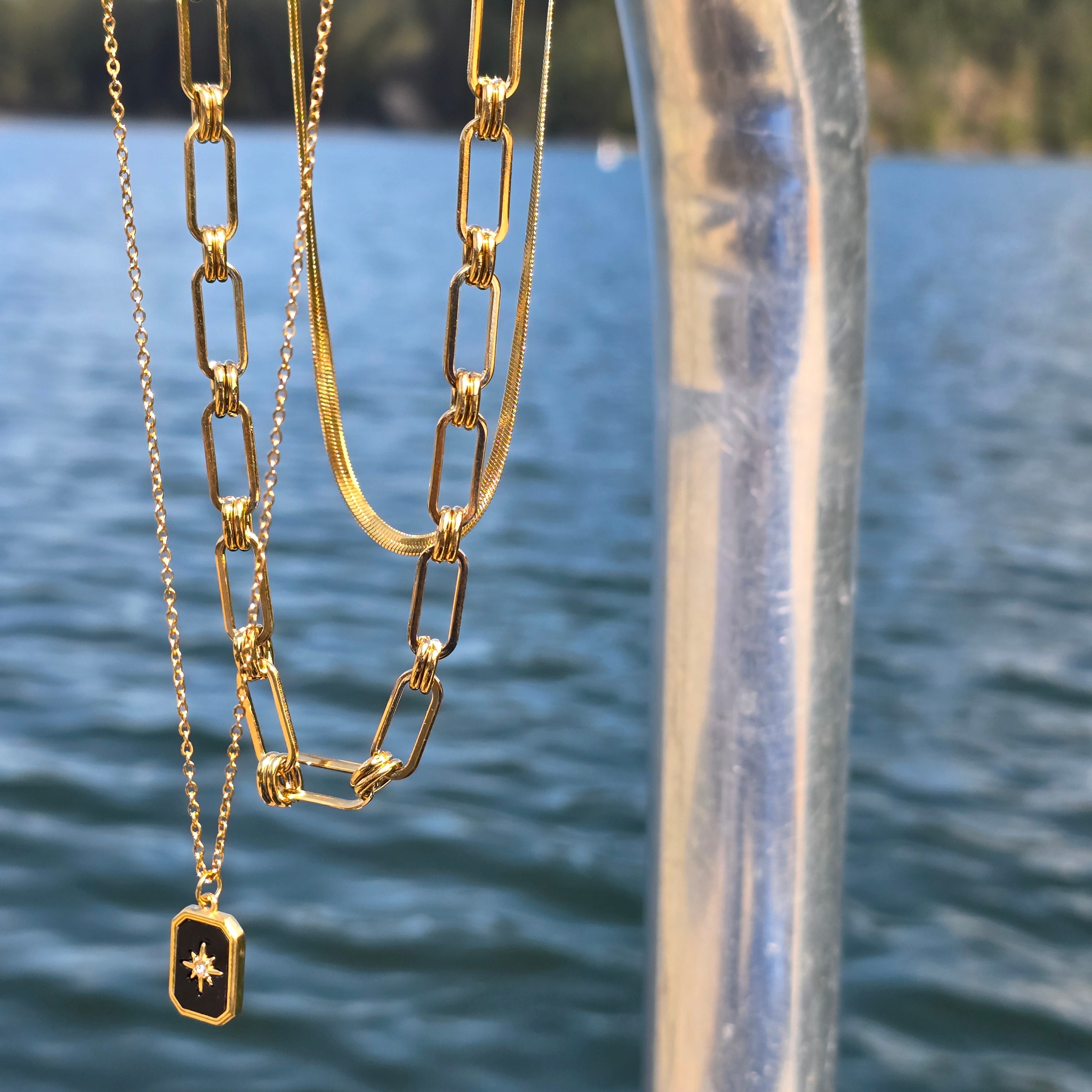 three gold necklaces hanging on pole at Cultus Lake in British Columbia