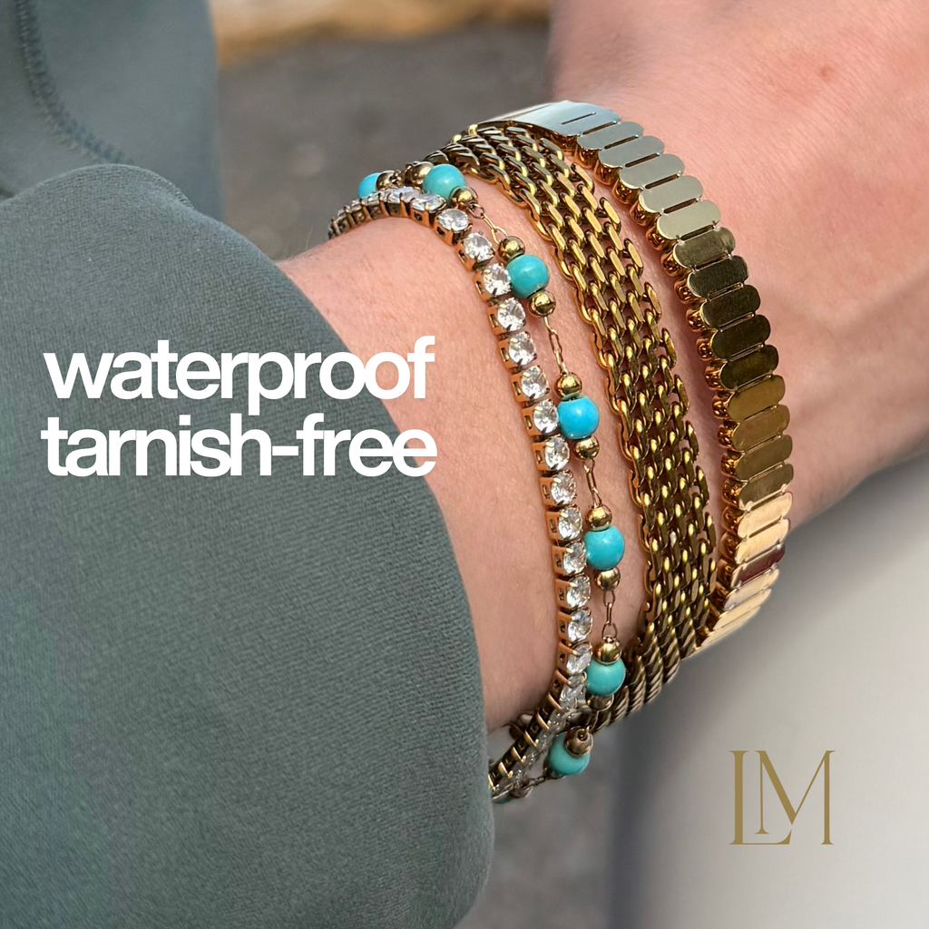 Close-up of a wrist wearing multiple bracelets with text 'waterproof tarnish-free' and a logo.